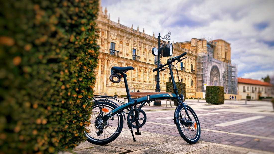 Stylish PACTO folding bike for urban commuting parked in a city square with historic buildings.