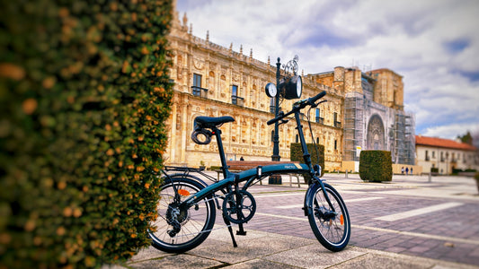 Stylish PACTO folding bike for urban commuting parked in a city square with historic buildings.
