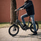 Man op zwart grijs PACTO elektrische  vouwfiets (folding bike) in stad compacte en moderne elektrische vouwfiets