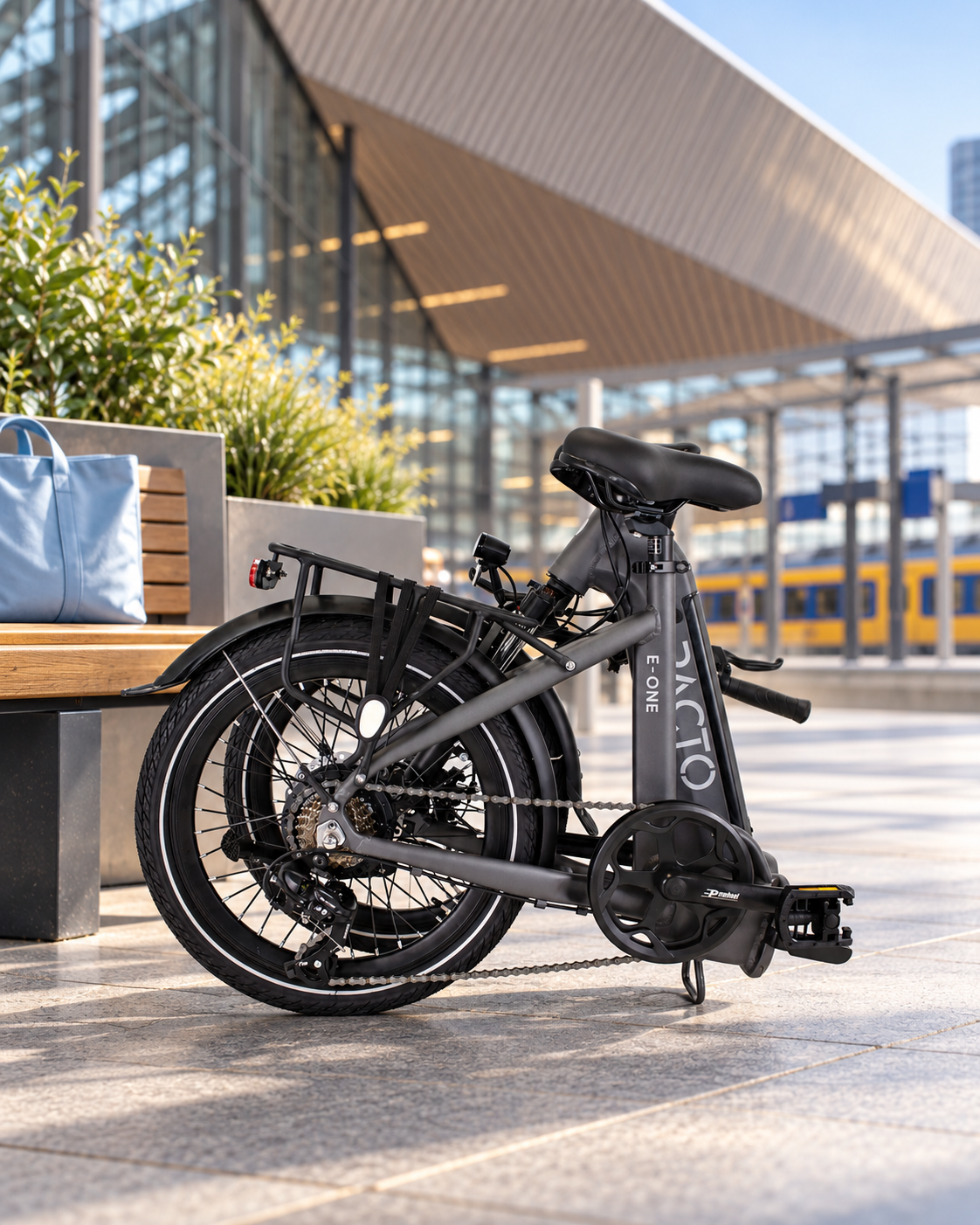 Nederlands
Opgevouwen grijze PACTO E‑ONE elektrische vouwfiets bij Rotterdam Centraal, klaar om mee te nemen in de trein.

English
Folded grey PACTO E‑ONE electric folding bike at Rotterdam Central Station, ready to take on the train.