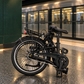 Nederlands:
Detail van de zwarte PACTO SEVEN vouwfiets met bagagedrager, achterwiel, achterrem, spatbord en kettingkast.

Engels:
Close-up of the black PACTO SEVEN folding bike, showing the rear rack, rear wheel, rear brake, mudguard and chain guard.